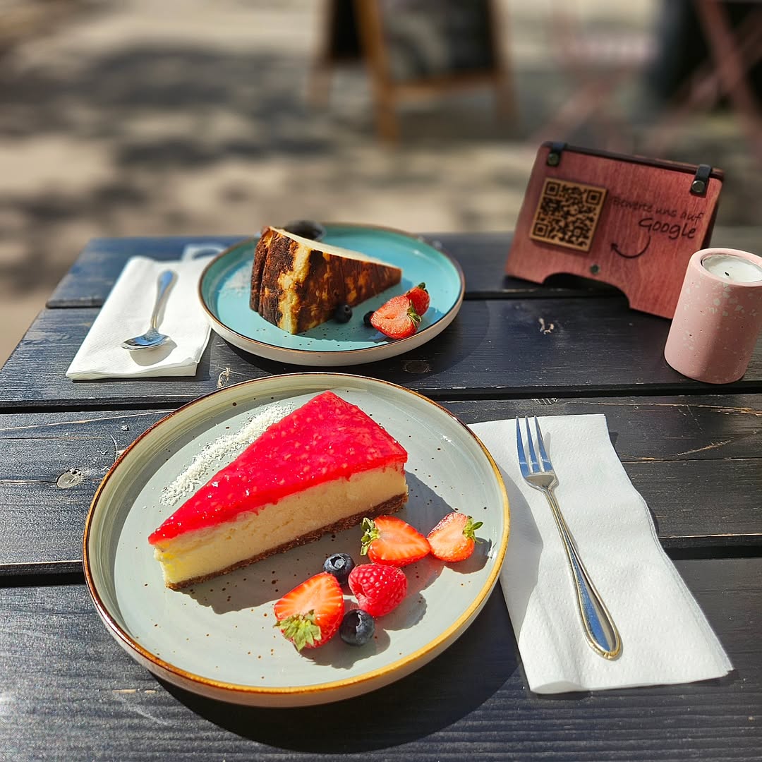 Veganes Frühstück Hamburg – frischer Cheesecake mit Beeren im Lovaena Café Wilhelmsburg auf sonnigem Tisch serviert