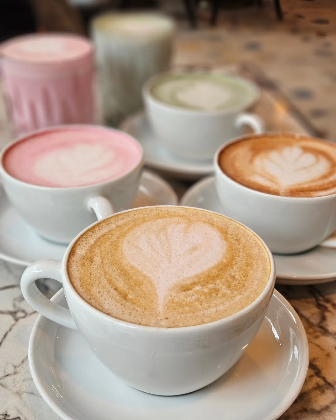 Assortment of colorful lattes with heart-shaped latte art served at Lovaena Café – a warm expression of Cafékultur Hamburg.