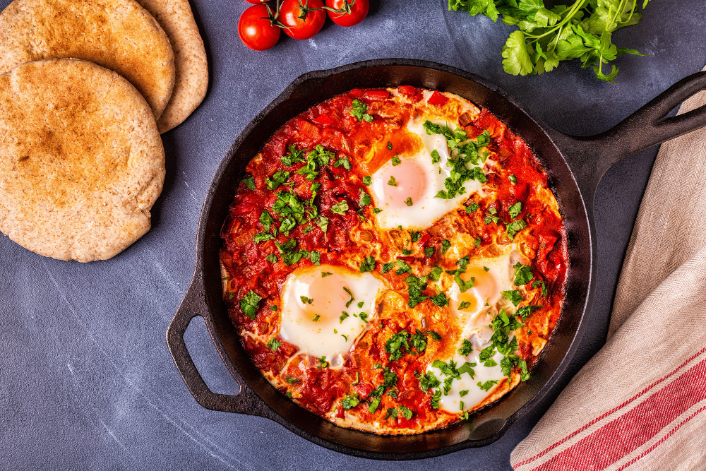 Veganes Shakshuka Hamburg im Lovaena Café serviert in Pfanne mit Tomaten-Paprika-Soße, geröstetem Gemüse und hausgemachtem Brot in Wilhelmsburg
