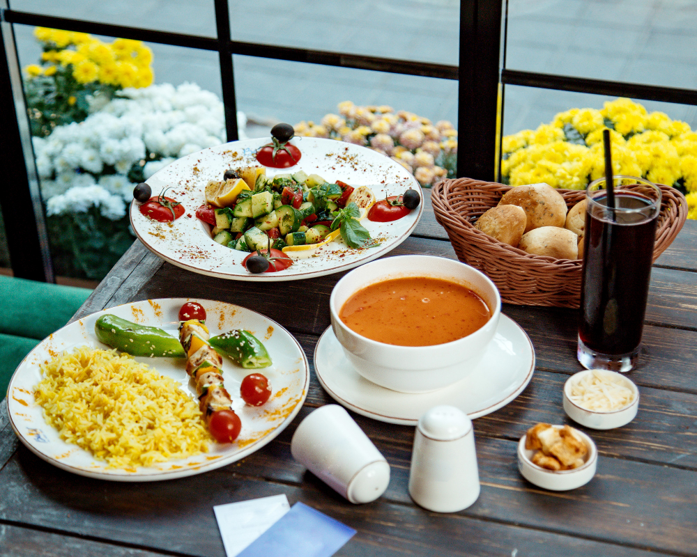 „Vegane Mahlzeit im Lovaena Café Hamburg Wilhelmsburg mit frischem Gemüsesalat, Suppe, gelbem Reis, Brot und Getränk – gesunde pflanzliche Ernährung voller Farbe und Geschmack.